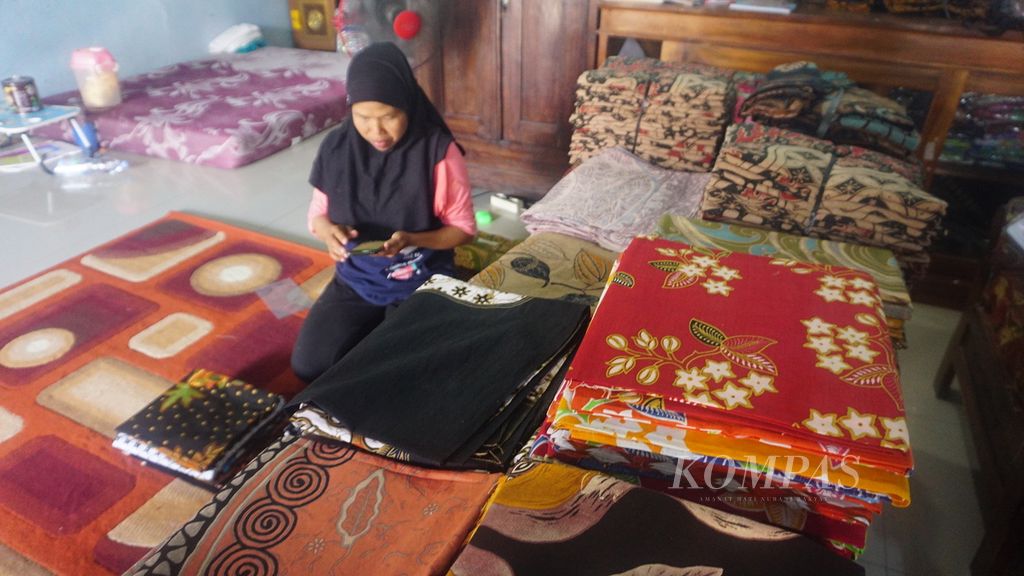 Sunarni, pemilik Batik Nurul Hidayah, menata kain batik dagangannya, di Desa Pilang, Kecamatan Masaran, Kabupaten Sragen, Jawa Tengah, Rabu (13/7/2022). Bisnis batik tersebut masih berskala UMKM. Optimalisasi pemasaran dilakukan secara digital untuk memperluas jangkauan pasar.