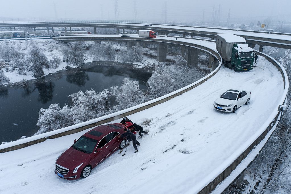 Mobil-mobil terjebak salju saat melintas di jalan tol akibat hujan salju lebat di Wuhan, Provinsi Hubei, China, 6 Februari 2024. 
