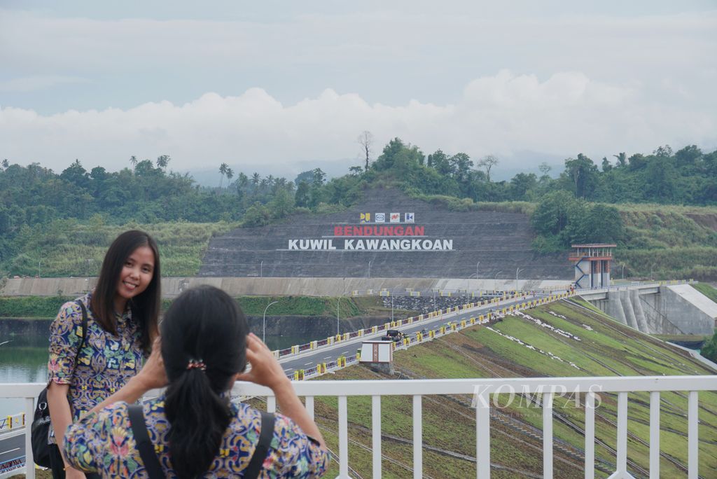Pegawai Badan Wilayah Sungai Sulawesi (BWSS) I berfoto dengan latar tulisan Bendungan Kuwil Kawangkoan, Rabu (18/1/2023), di Kalawat, Minahasa Utara, Sulawesi Utara, itu. 