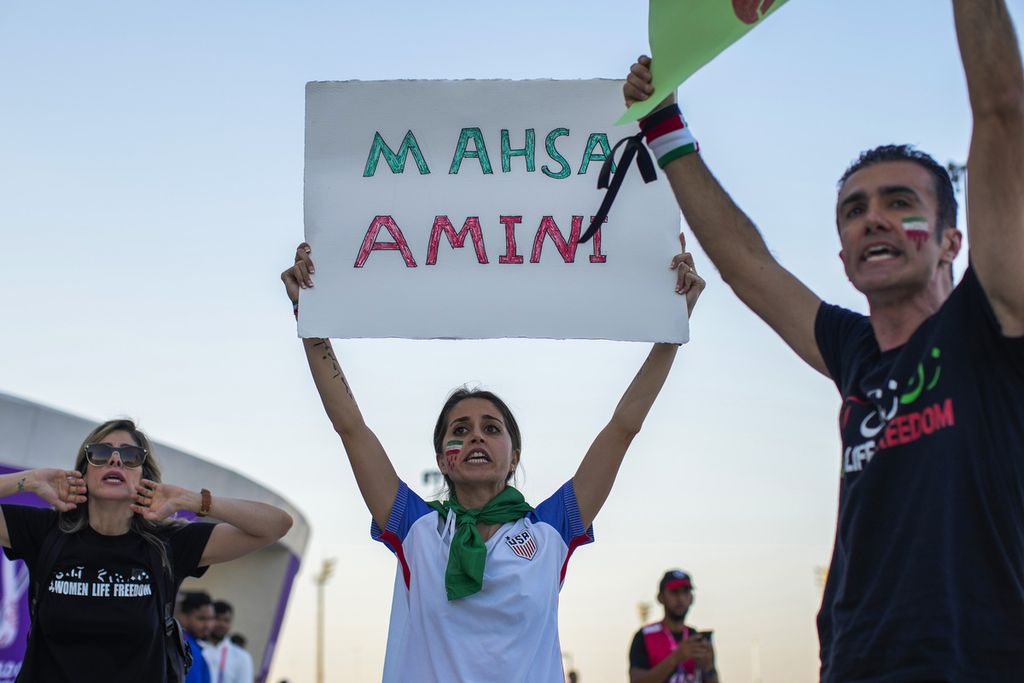 Warga membawa kertas yang bertuliskan Mahsa Amini, perempuan Iran yang tewas ketika tengah menjalani "pendidikan tentang moralitas" oleh polisi moral Iran, jelang pertandingan babak penyisihan grup Piala Dunia 2022 antara Iran dan Wales di Doha, Qatar, , Jumat (25/11/2022). 