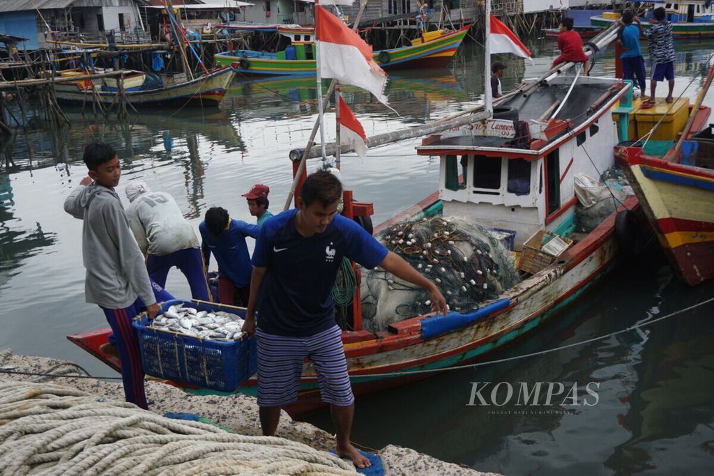 Nelayan menurunkan ikan hasil tangkapan dari perahu ke tempat pendaratan ikan Gudang Lelang, Kota Bandar Lampung, Lampung, Rabu (23/1/2019). Gelombang tinggi dan angin kencang membuat sebagian nelayan takut melaut.