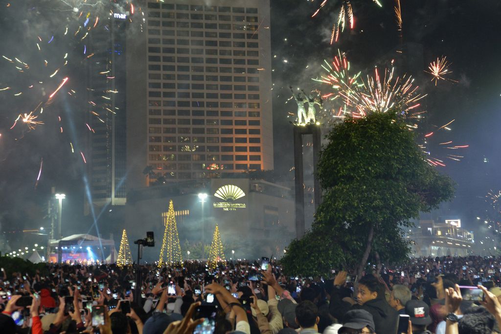 Warga menyaksikan pertunjukan kembang api di sekitar Bundaran Hotel Indonesia (HI), Jakarta Pusat, Minggu (1/1/2023). Bundaran HI menjadi salah satu kawasan yang dipilih warga untuk merayakan Tahun Baru 2023. Tidak hanya kembang api, warga juga disuguhi penampilan sejumlah penampilan musik di panggung Malam Muda Mudi. 