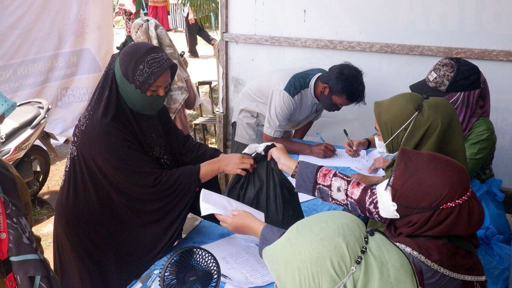 Warga menerima paket bahan pokok setelah divaksin dalam kegiatan vaksinasi bergerak pada Ramadhan 1443 H di Puskesmas Berangas, Kecamatan Alalak, Barito Kuala, Kalimantan Selatan, Kamis (7/4/2022). 