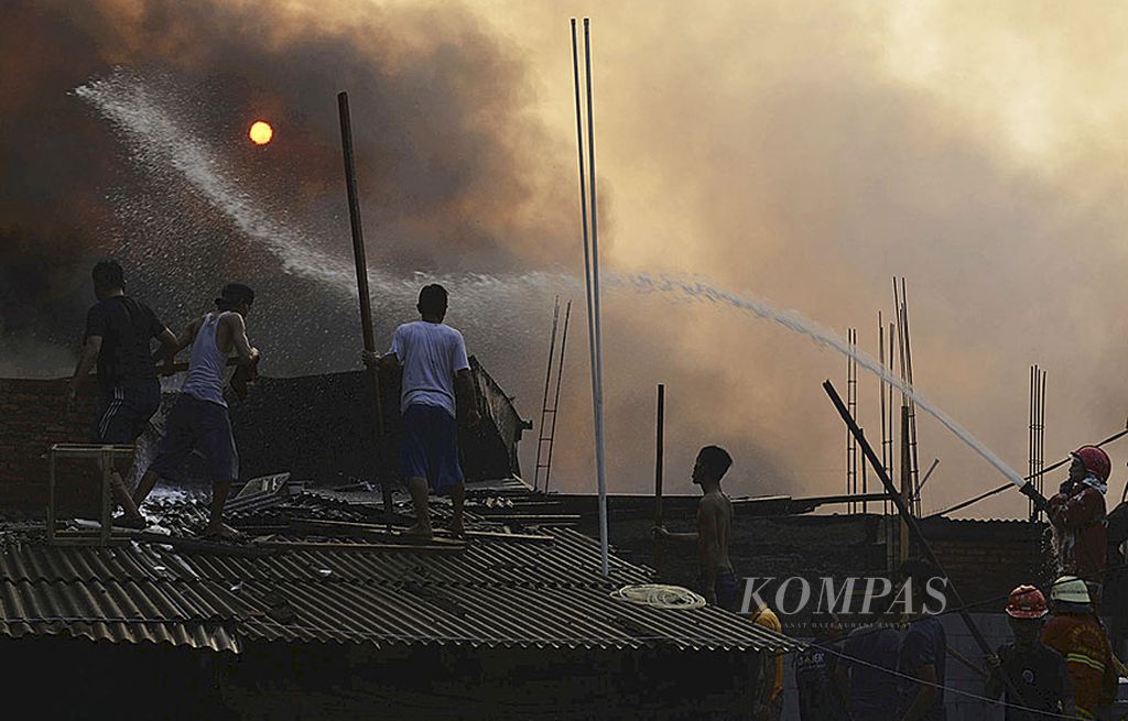 Warga dan petugas  berusaha memadamkan kobaran api yang membakar permukiman padat penduduk di Kebon Pala, Kampung Melayu, Jatinegara, Jakarta Timur, Minggu (20/8). Belum diketahui pasti penyebab kebakaran.