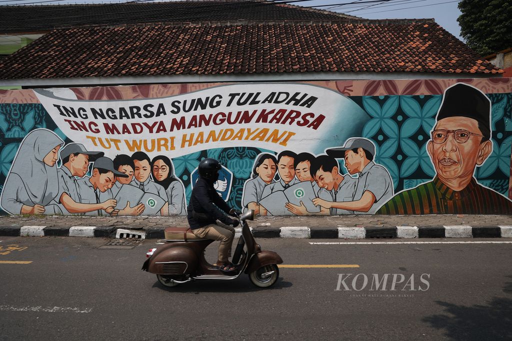 Warga melintas di depan mural tentang semboyan dari Ki Hajar Dewantara yang dilukis di tembok pagar SMP Negeri 9 Yogyakarta, Kotagede, Yogyakarta, Jumat (24/3/2023). 