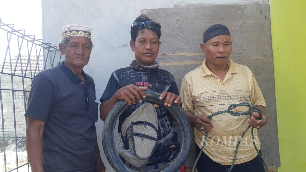 Tili (35, tengah) bersama Laoding (72, kiri) dan Nurdin (62, kanan) memperlihatkan ban yang sudah dipotong dari leher buaya muara dan sisa tali yang dipakai untuk menjerat buaya tersebut di Desa Tinggede, Kecamatan Marawola, Kabupaten Sigi, Sulteng, Selasa (8/2/2022).