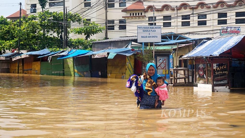 Warga dengan menggendong anaknya menyeberang Jalan Dayeuhkolot, Kabupaten Bandung, yang tergenang banjir, Senin (8/4/2019).