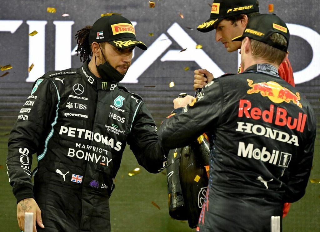 Pebalap Mercedes, Lewis Hamilton (kiri), menyalami rivalnya, Max Verstappen (kanan) yang menjadi juara dunia pada seri penutup Formula 1 musim 2021 di Sirkuit Yas Marina, Abu Dhabi, Uni Emirat Arab, 12 Desember 2021 lalu.