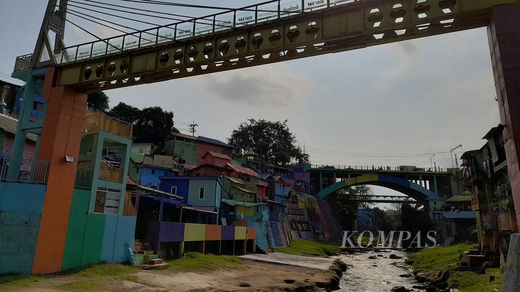 Air Sungai Brantas mengalir dengan debit tidak terlalu besar di bawah Jembatan Brantas (belakang) dan jembatan kaca (depan) yang menghubungkan Kampung Warna-warni di Kelurahan Jodipan dan Kampung Tiga Dimensi (Tridi) di Kelurahan Kesatrian, Kecamatan Blimbing, Kota Malang, Jawa Timur, Sabtu (9/7/2022).