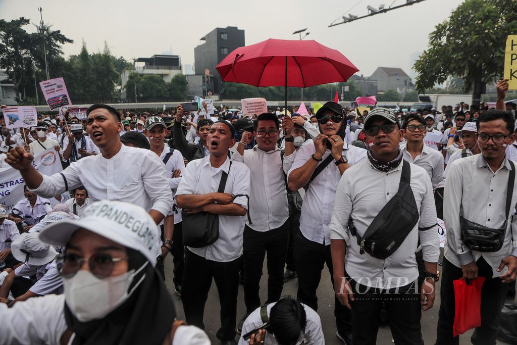 Peserta aksi membawa payung untuk menghindari panas matahari di depan Gedung DPR, Jakarta, Senin (7/8/2023). 