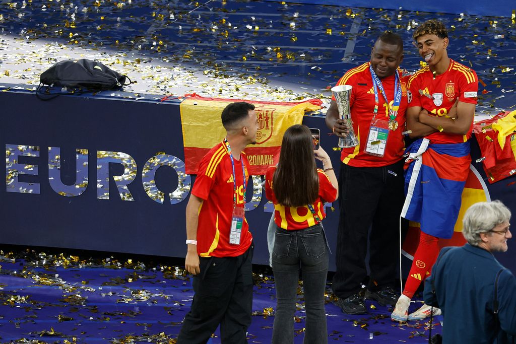 Penyerang dan bintang muda Spanyol, Lamine Yamal, merayakan bersama keluarganya setelah memenangkan pertandingan sepak bola final Piala Eropa 2024 antara Spanyol dan Inggris di Stadion Olimpiade Berlin, Jerman, Senin (15/7/2024) dini hari WIB.