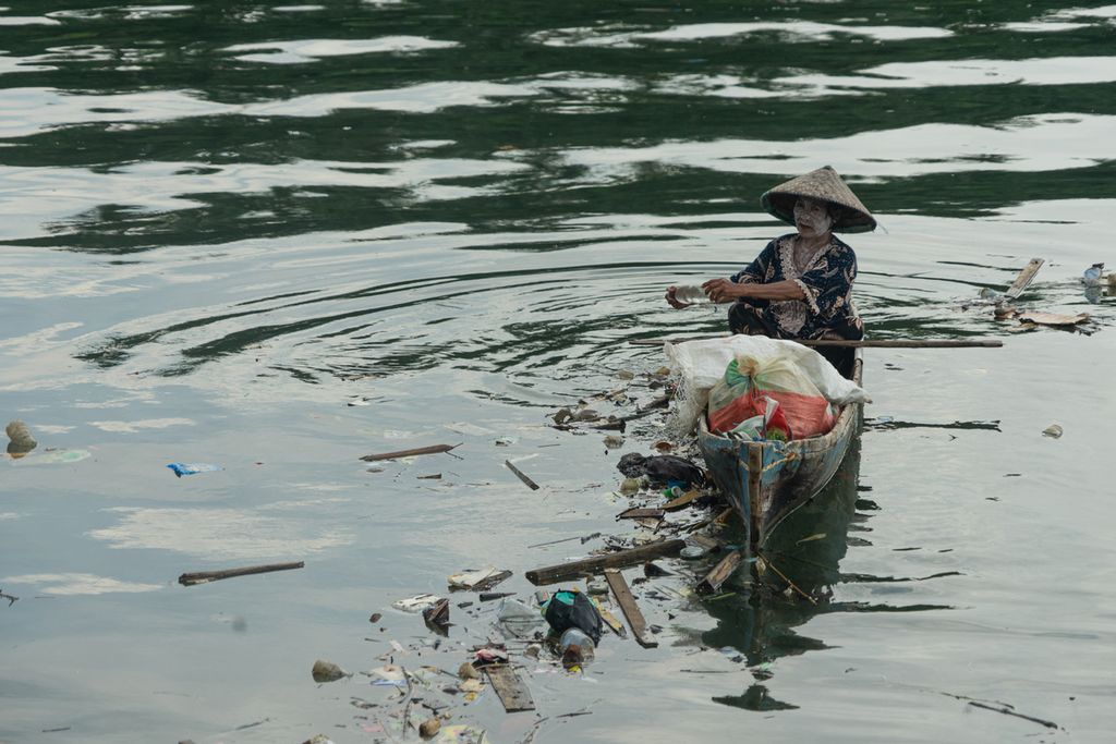 Hanafiah (60) memungut sampah plastik dari pesisir Teluk Kendari, Sulawesi Tenggara, Minggu (2/1/2022).