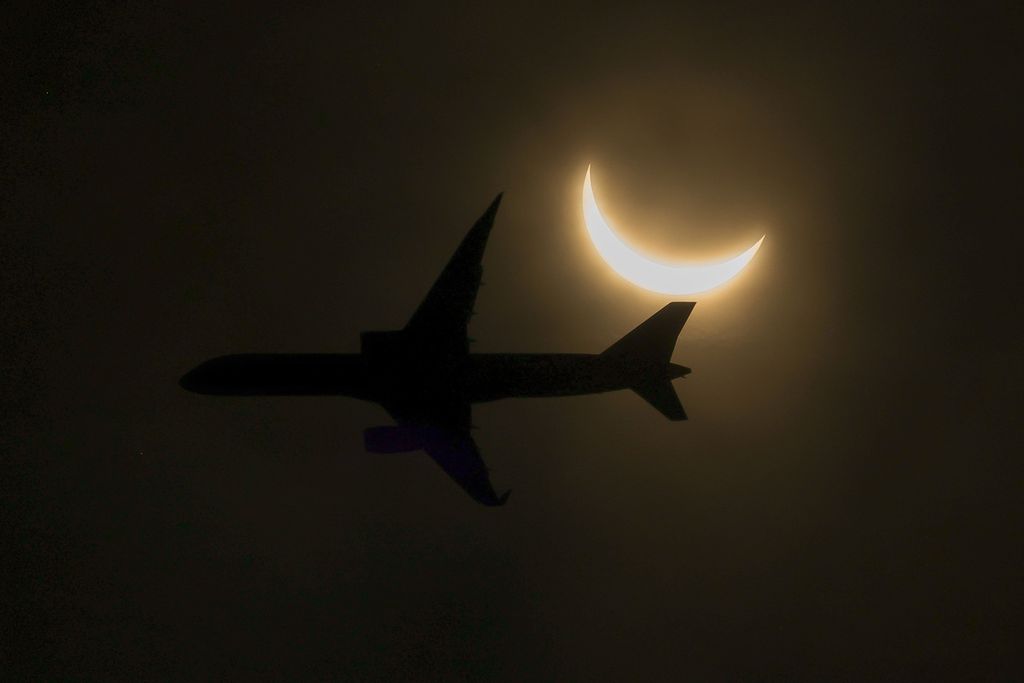 Sebuah pesawat terbang melintas saat terjadi gerhana matahari, Senin (8/4/2024) di Glen Rock, New Jersey, Amerika Serikat. Jutaan orang berbondong-bondong ke wilayah Amerika Utara untuk menyaksikan gerhana matahari total. 