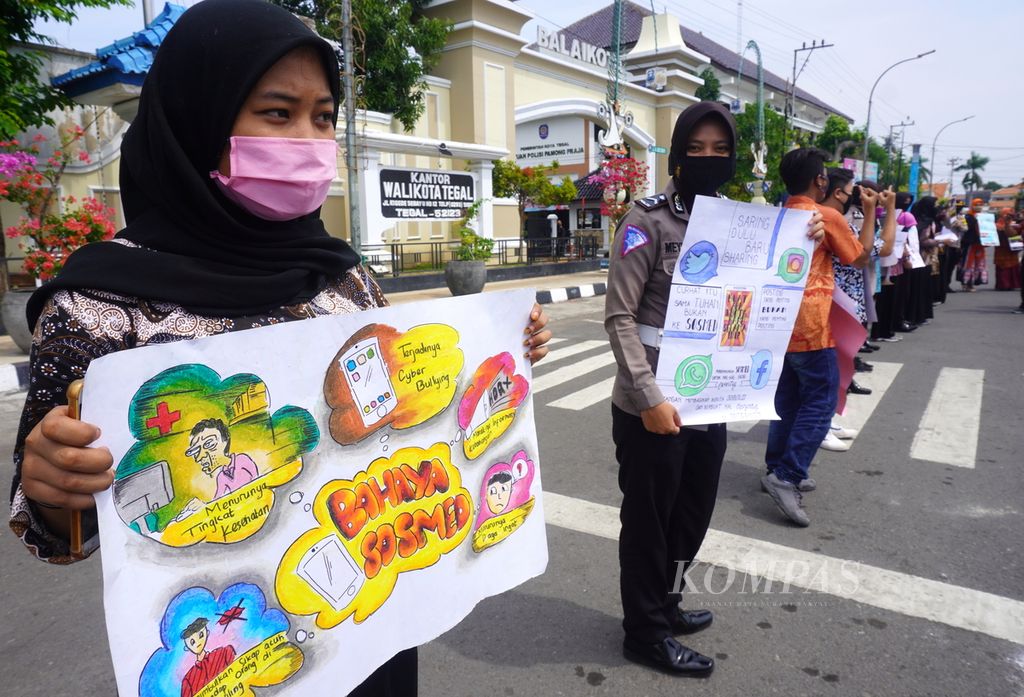 Anak-anak membawa poster tentang bahaya media sosial dalam kampanye melawan kekerasan terhadap anak, Kamis (23/7/2020), di Kota Tegal, Jawa Tengah. 