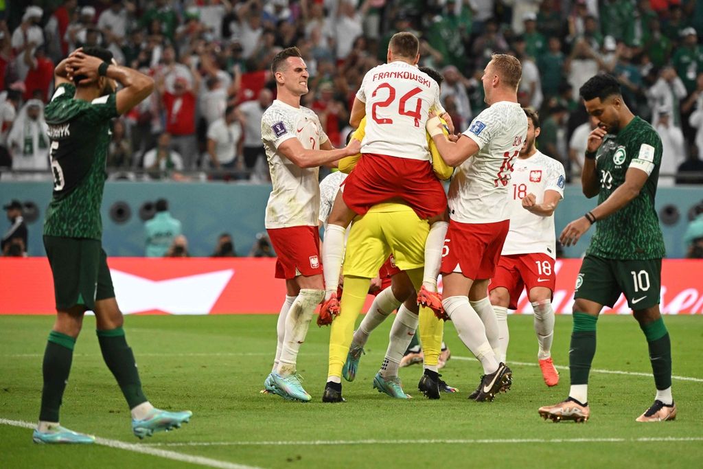 Kiper Polandia, Wojciech Szczesny (kaus kuning), dirangkul rekan-rekan setimnya seusai menggagalkan penalti Arab Saudi pada laga penyisihan Grup C Piala Dunia Qatar 2022 di Stadion Education City, Al-Rayyan, Qatar, Sabtu (26/11/2022) malam. Polandia menang, 2-0. 