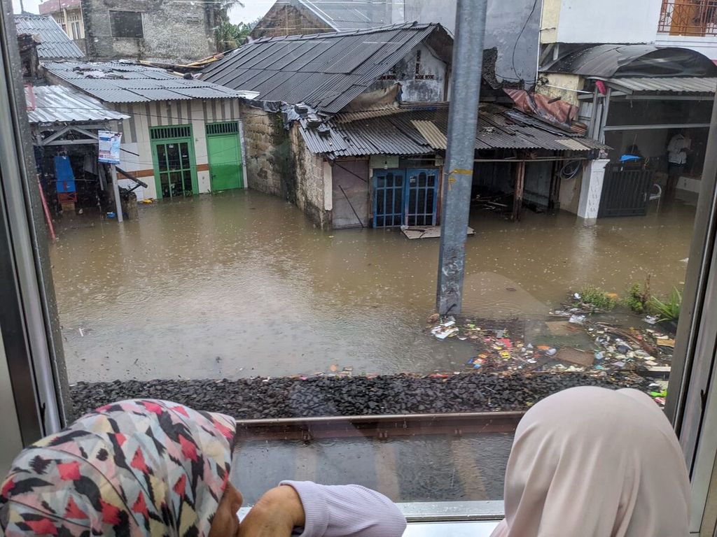 Penumpang KRL melihat banjir di wilayah Jakarta, Sabtu (6/7/2024).