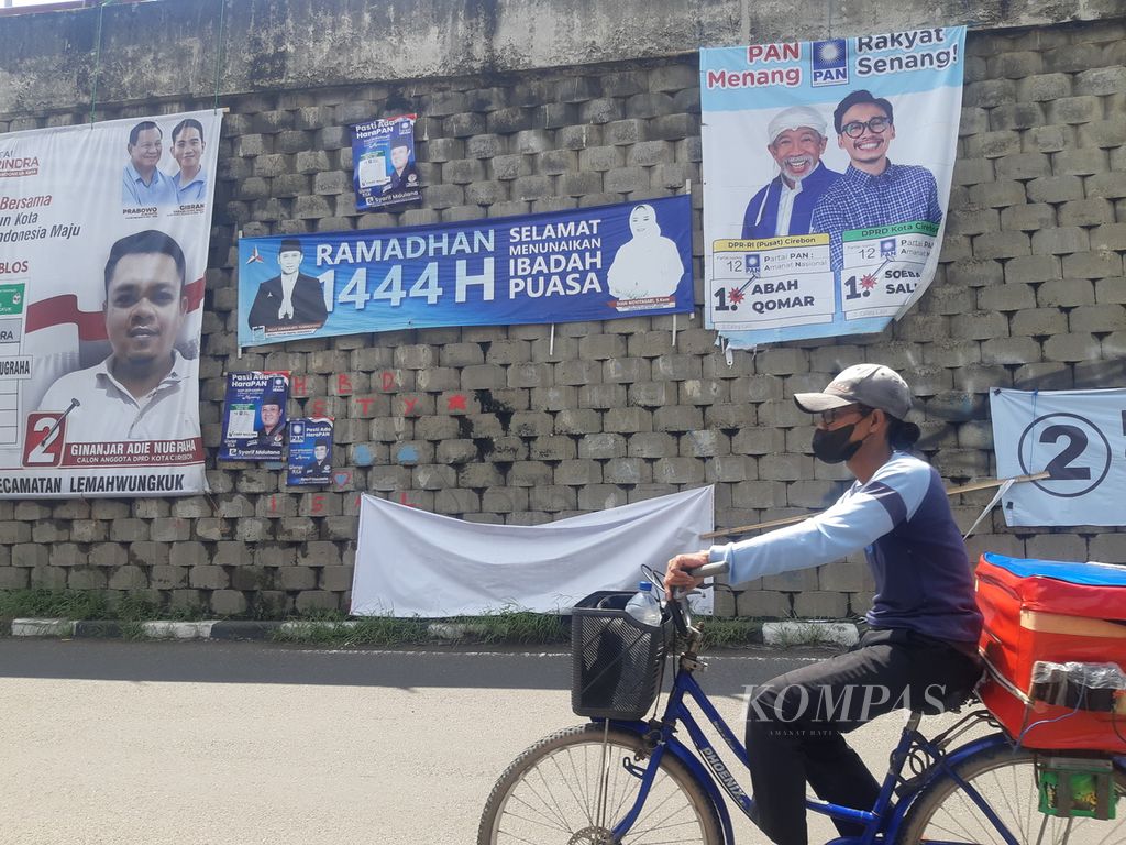 Warga melintas di depan spanduk salah satu calon anggota legislatif DPR Daerah Pemilihan Jawa Barat VIII di Kota Cirebon, Jawa Barat, Jumat (2/2/2024). Sebanyak 152 caleg di daerah itu bersaing memperebutkan sembilan kursi DPR.