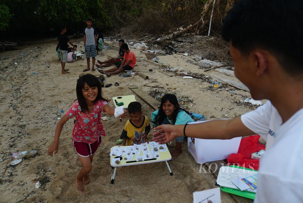 Tiga bocah yang belum lancar membaca, yakni Arif (8), Fatin (8), dan Dewi (13), bermain gim alfabet bersama Farlan Erlangga (22), Sabtu (18/11/2023), dalam kelas informal yang digelar komunitas literasi Aksara Manado di Pulau Bunaken, Manado, Sulawesi Utara. 