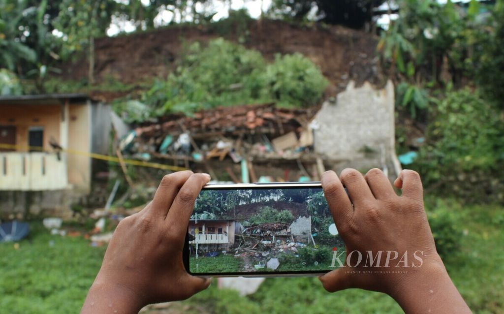Warga memotret lokasi longsor di Kelurahan Citeureup, Kota Cimahi, Jawa Barat, Sabtu (27/4/2019). Longsor pada Jumat malam itu menimpa rumah warga serta menewaskan dua anak dan melukai enam orang lainnya.