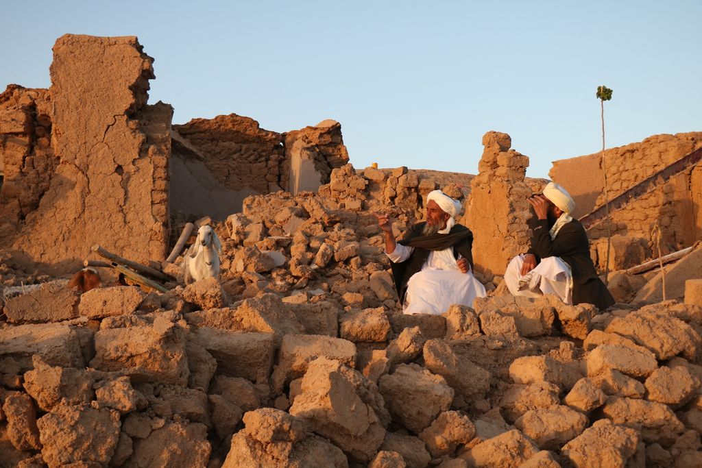 Warga duduk di dekat rumah yang hancur akibat gempa di Desa Sarbuland, Distrik Zendeh Jan, Provinsi Herat, Afghanistan, Sabtu (7/10/2023). 
