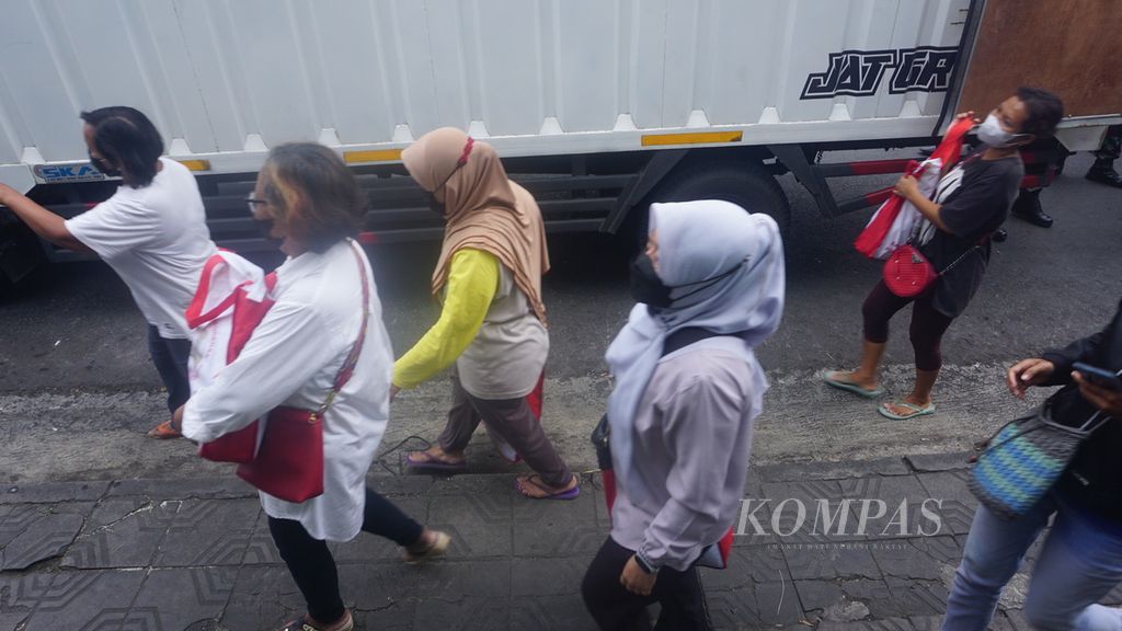 Warga menenteng tas berisikan bantuan dari Presiden Joko Widodo yang dibagikan di Pasar Serangan, Yogyakarta, Jumat (1/5/2022). Total ada 1.200 paket bantuan yang dibagikan. Warga antusias menyambut pembagian bantuan berisi bahan pokok tersebut.