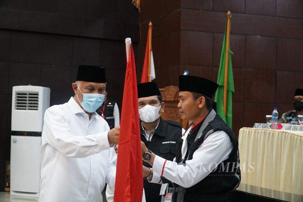 Gubernur Sumatera Barat Mahyeldi menyerahkan bendera Merah Putih kepada ketua kloter I jemaah haji embarkasi Padang saat acara pelepasan di Aula Asrama Haji Padang, Sumatera Barat, Sabtu (4/6/2022). 