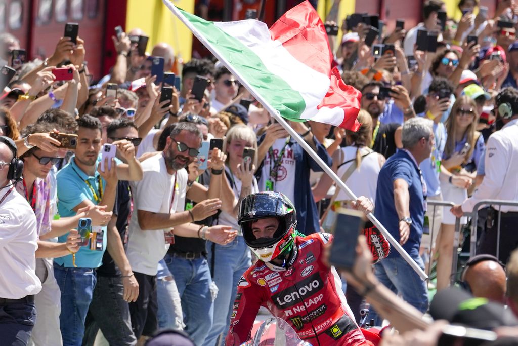 Pebalap Ducati Lenovo Francesco Bagnaia melakukan selebrasi dengan membawa bendera Italia seusai balap MotoGP seri Italia di Sirkuit Mugello, Minggu (11/6/2023). 