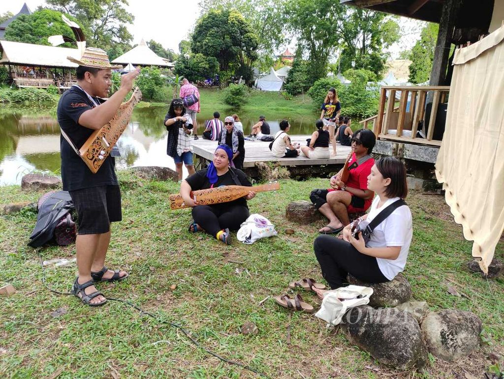 Beberapa pengunjung belajar memainkan sape di sela Rainforest World Music Festival 2024 di Kuching, Sarawak, Malaysia, Sabtu (29/6/2024).