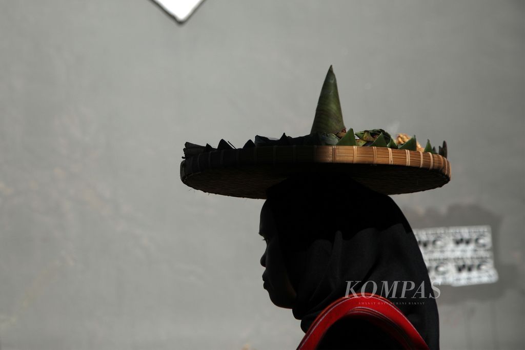 Seorang perempuan menyunggi nampan berisi makanan tradisional saat arak-arakan parade Nyiru Jaja Bejangkongan di Desa Pringgasela Selatan, Kecamatan Pringgasela, Lombok Timur, Nusa Tenggara Barat, Rabu (20/12/2023). 