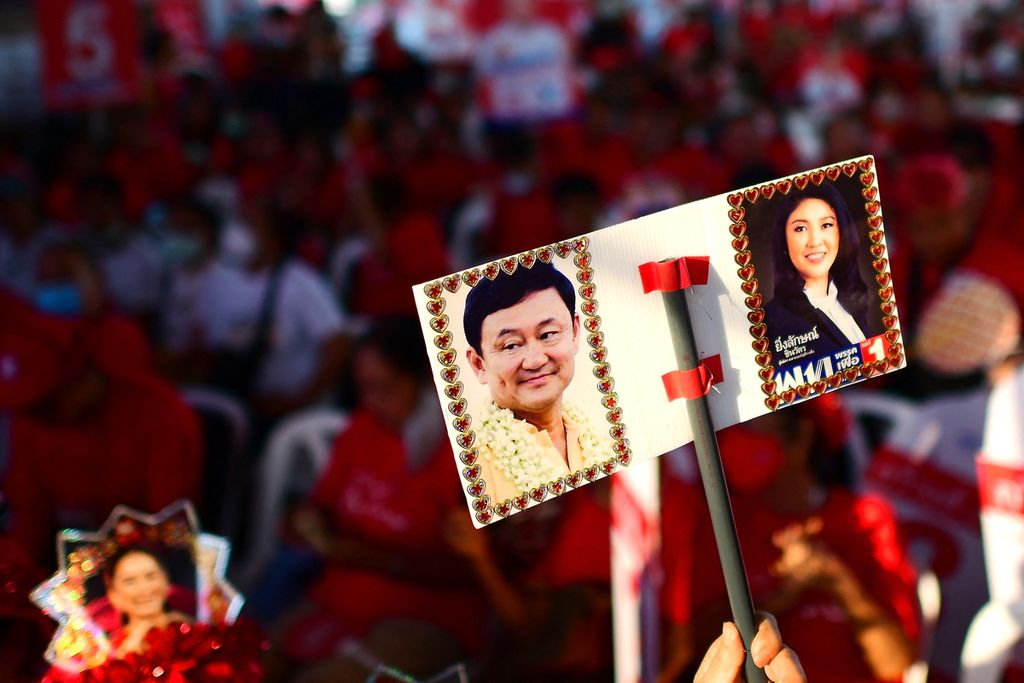 Foto yang diambil pada 28 April 2023 ini memperlihatkan plakat yang dibawa seorang pendukung Partai Pheu Thai, bergambar foto dua mantan Perdana Menteri Thailand, kakak-beradik Thaksin Shinawatra (kiri) dan Yingluck Shinawatra, dalam kampanye Partai Pheu Thai di Bangkok, Thailand. 