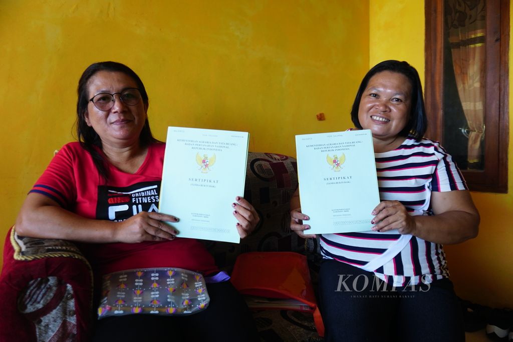 Vera Tatawi (42, kiri) dan Nova Kalompo menunjukkan sertifikat tanah milik mereka di Desa Mangkit, Kecamatan Belang, Minahasa Tenggara, Sulawesi Utara, Selasa (9/1/2024). Sebanyak 400 dari 1.050 sertifikat tanah yang dibagikan kepada warga desa tersebut pada akhir 2018 hingga awal 2019 diterima oleh perempuan.