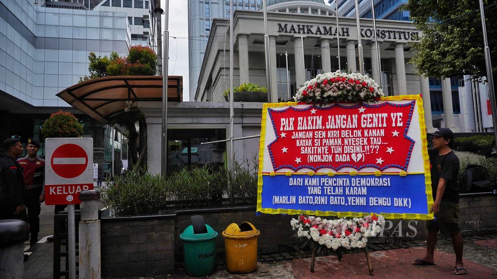 Seorang kurir karangan bunga memasang karangan bunga di depan Mahkamah Konstitusi, Jakarta, menjelang rangkaian sidang perkara Perselisihan Hasil Pemilihan Umum (PHPU), Selasa (26/3/2024).