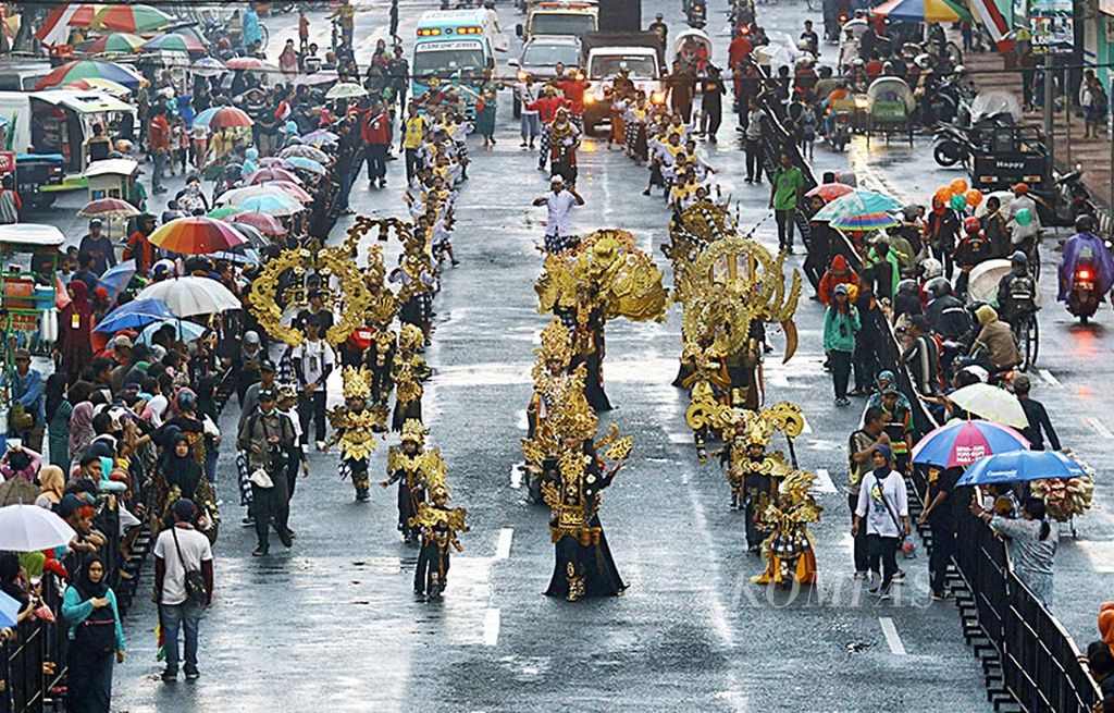 Warga menyaksikan defile Jember Fashion Carnaval yang melintas di jalan-jalan protokol sepanjang 3 kilometer di Jember, Jawa Timur, Kamis (10/8). Berkat Jember Fashion Carnaval, Kabupaten Jember ditetapkan sebagai kota karnaval pertama di Indonesia.