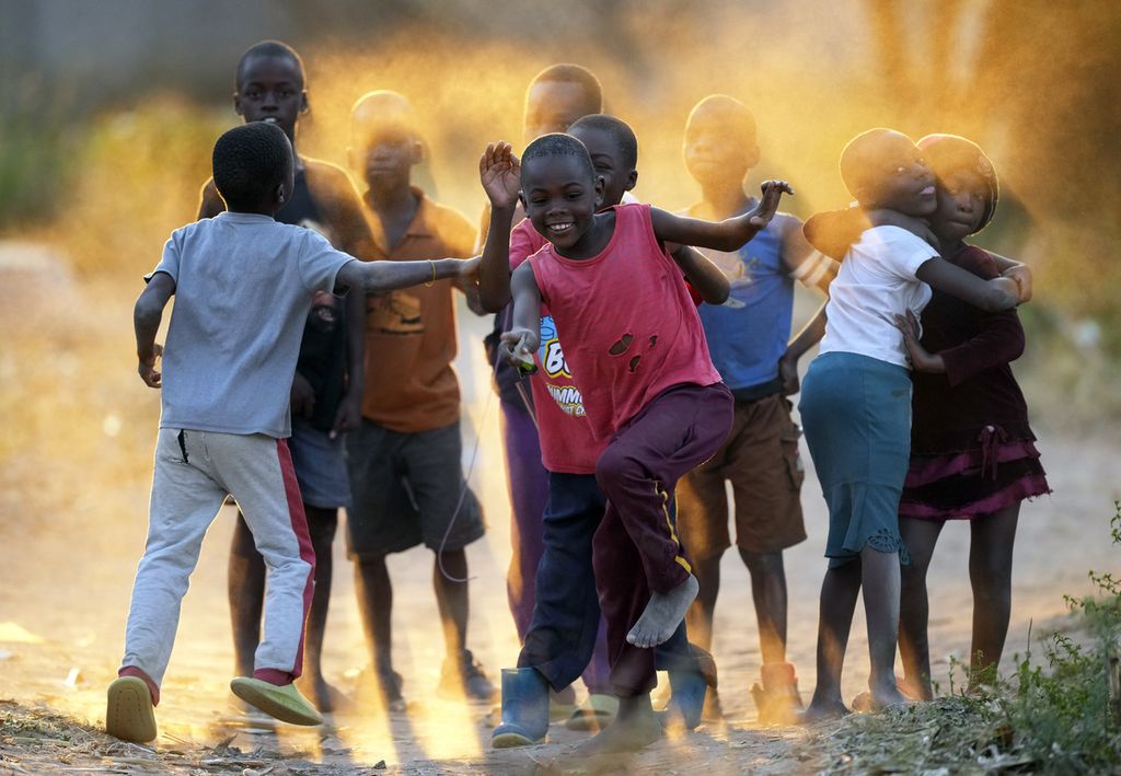 Anak-anak bermain di antara debu jalanan kampung Epworth yang berada di pinggiran kota Harare, Zimbabwe, Rabu (15/6/2022).