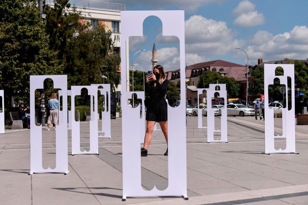 Seorang wanita berjalan melewati karton berbentuk manusia yang ditampilkan untuk memperingati Hari Internasional Korban Penghilangan Paksa di Pristina, Kosovo, Senin (30/8/2021). Sejak berakhirnya perang Kosovo pada 1998-1999, sekitar 1.630 orang yang sebagian besar adalah warga Albania masih dianggap hilang. 