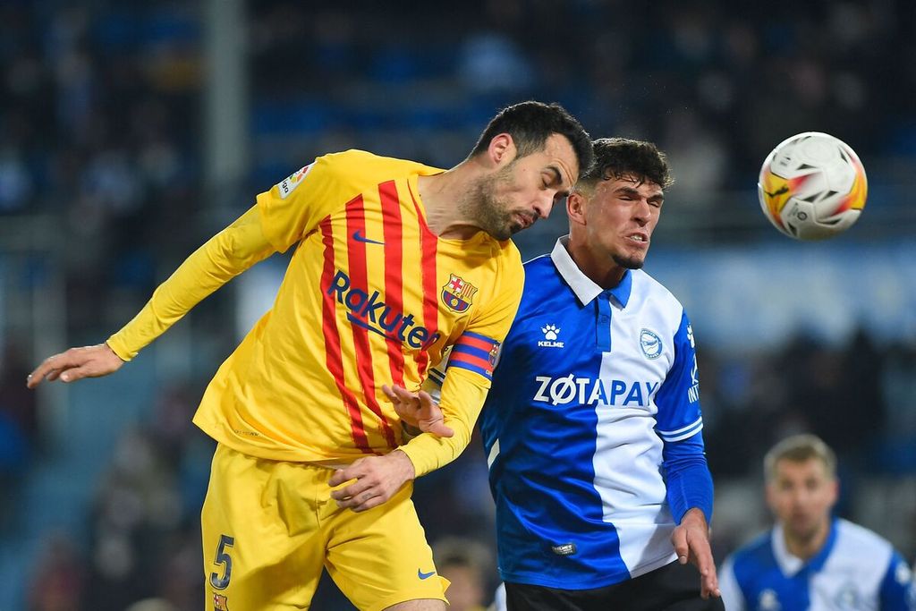 Pemain Barcelona Sergio Busquets (kiri) menyundul bola dengan dibayangi pemain Alaves Javi Lopez pada laga Liga Spanyol di Stadion Mendizorroza, Vitoria, Spanyol, Senin (24/1/2022) dini hari WIB. Barcelona memenangi laga itu dengan skor 1-0.