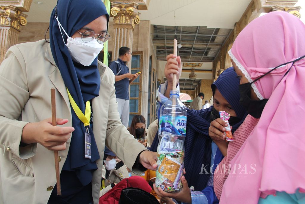 Mahasiswi Universitas Gadjah Mada (UGM) mengajari sejumlah anak cara membuat <i>ecobrick</i> atau bata ramah lingkungan di halaman sebuah masjid di kawasan Sungsang, Kecamatan Banyuasin II, Kabupaten Banyuasin, Sumatera Selatan, Minggu (23/1/2022). 