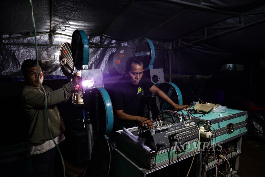 Petugas operator mengoperasikan proyektor yang memutar film seluloid 35 mm dalam festival layar tancap di lapangan di Babakan, Kecamatan Setu, Tangerang Selatan, Banten, Rabu (18/1/2023) malam. Kegiatan tersebut dalam rangka syukuran memperingati hari ulang tahun komunitas pencinta film LCD Tangerang Selatan.