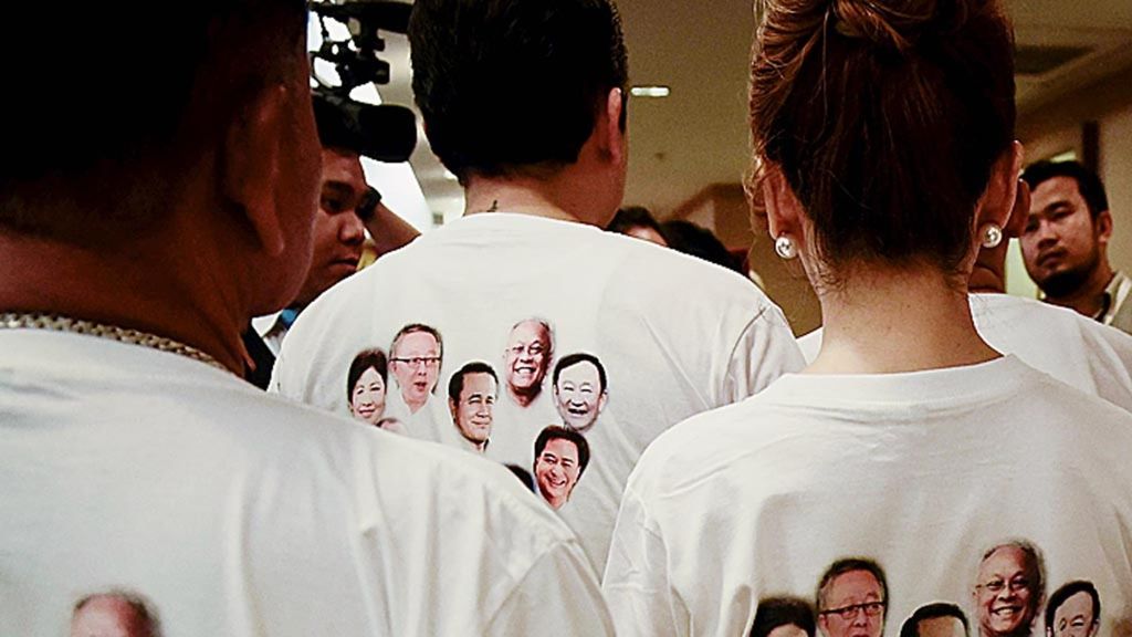 Anggota Phure Chart Thai Club mengenakan kaos bergambar wajah-wajah kontestan politik, termasuk Perdana Menteri Thailand Prayuth Chan-O-Cha (kiri) dan sejumlah bekas perdana menteri seperti Thaksin Shinawatra (atas kanan) dan Yingluck Shinawatra (kiri atas) di kantor Komisi Pemilihan Umum Thailand di Bangkok, 2 Maret 2018. (AFP PHOTO / Lillian SUWANRUMPHA)