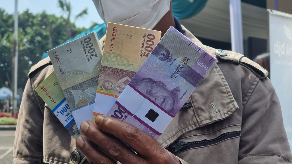 Salah seorang warga menunjukkan uang hasil penukaran dari kendaraan layanan penukaran kas keliling di Kantor Perwakilan Bank Indonesia Jawa Barat, Kota Bandung, Senin (11/4/2022)