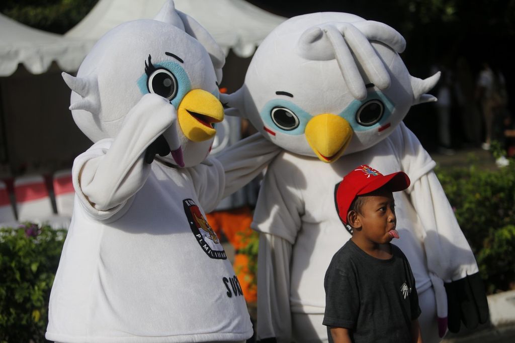 Seorang anak berpose bersama dua maskot Pemilu 2024, Sura dan Sulu, ketika KPU Provinsi DKI Jakarta menggelar sosialaisasi tahapan pemilihan umum 2024 saat hari bebas kendaraan bermotor di kawasan Bundaran Hotel Indonesia, Jakarta, Minggu (14/1/2024). Acara sosialisasi ini bertujuan untuk meningkatkan partisipasi pemilih dalam pemilu.