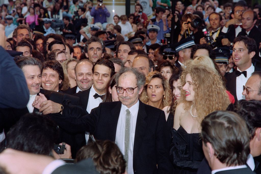 Sutradara Perancis-Swiss Jean-Luc Godard (tengah) didampingi oleh aktor Perancis Alain Delon (kiri) dan aktris Italia Domiziana Giordano (kanan). Mereka tiba untuk pemutaran filmnya, <i>Nouvelle Vague</i>, selama Festival Film Cannes ke-43, di Cannes, Perancis, 18 Mei 1990.