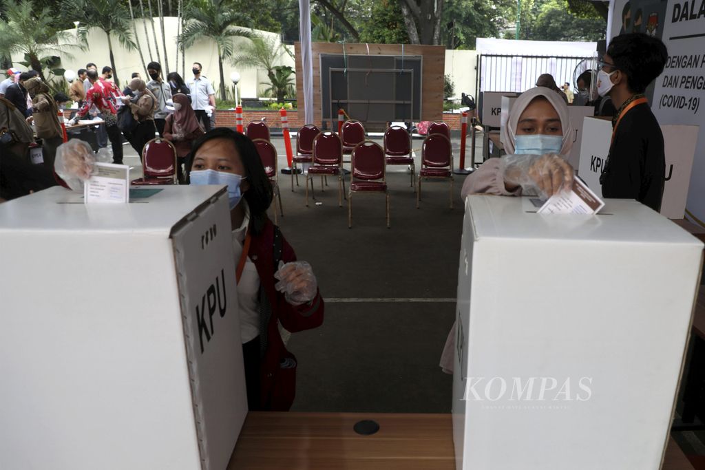 Pemilih menggunakan masker dan sarung tangan plastik saat  memasukkan surat suara ke dalam kotak suara di simulasi pemungutan suara pilkada serentak 2020 di Kantor KPU, Jakarta, Rabu (22/7/2020). Simulasi dilakukan dengan menerapkan protokol kesehatan pencegahan dan pengendalian Covid-19.