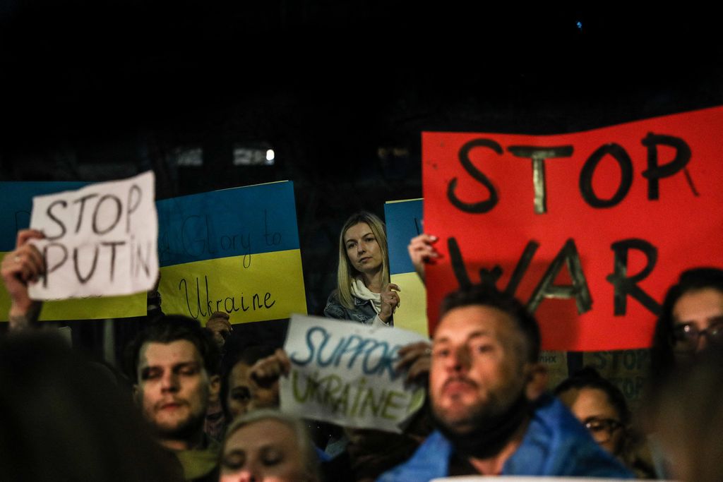 Seorang demonstran memegang tanda yang menggambarkan Ukraina dan bertuliskan "Hands off!" selama protes terhadap operasi militer Rusia di Ukraina, di depan kedutaan besar Rusia di Lisbon, Portugal, Kamis (24/2 2022).