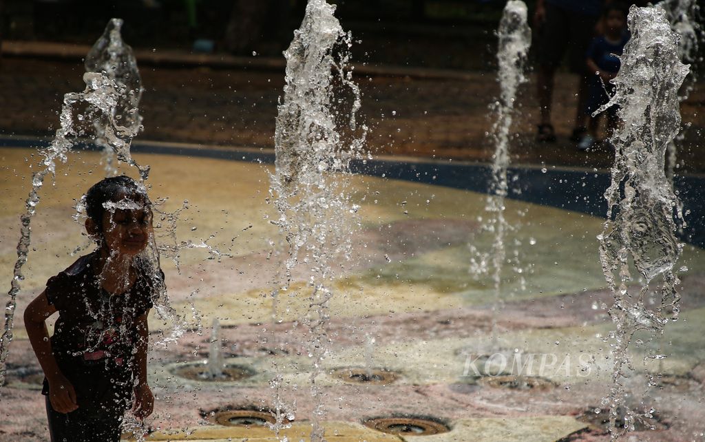 Seorang anak bermain air mancur di Taman Gandaria Tengah, Kramat Pela, Kebayoran Baru, Jakarta Selatan, Minggu (1/10/2023). Hal ini ia lakukan untuk mengusir rasa gerah akibat cuaca panas.