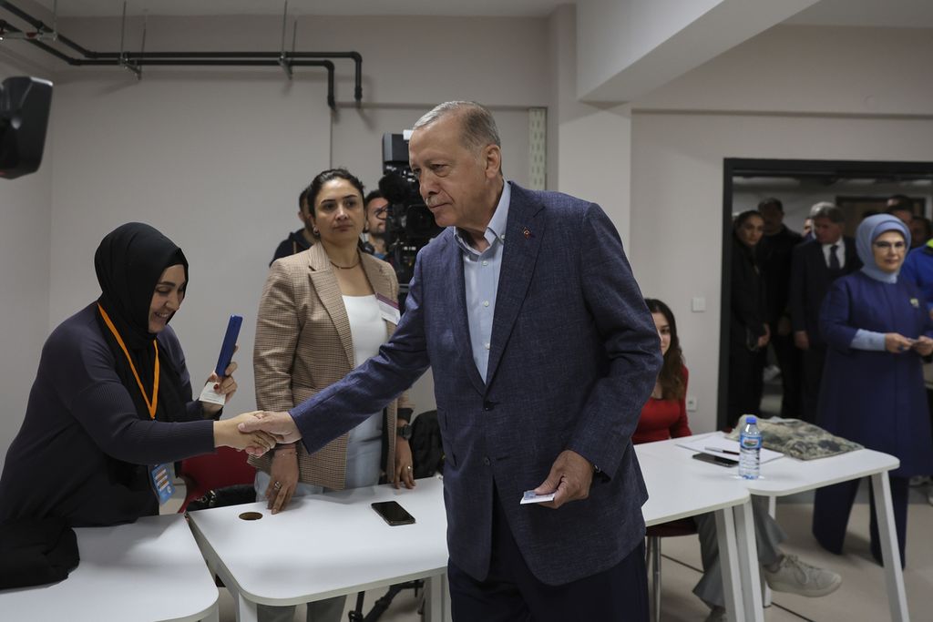 Presiden Turki Recep Tayyip Erdogan menyalami seorang perempuan saat tiba di sebuah tempat pemungutan suara di Istanbul, Turki, Minggu (14/5/2023). 