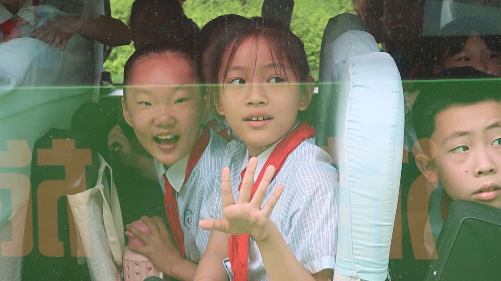 Anak-anak dalam bus sekolah tersenyum dan melambaikan tangan kepada rombongan wartawan Asia Pasifik yang merupakan peserta program pelatihan dari China International Press Communication Center Program (CIPCC) 2023 ketika berpapasan di sebuah persimpangan di Kota Weifang, Shandong, China, Rabu (24/5/2023), pagi