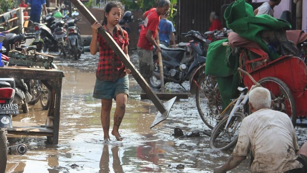 Warga membersihkan lingkungan permukiman dari lumpur yang terbawa banjir di Kelurahan Banyuanyar, Banjarsari, Solo, Jawa Tengah, Kamis (23/4). Ribuan rumah terendam banjir akibat meluapnya Kali Pepe di Solo.