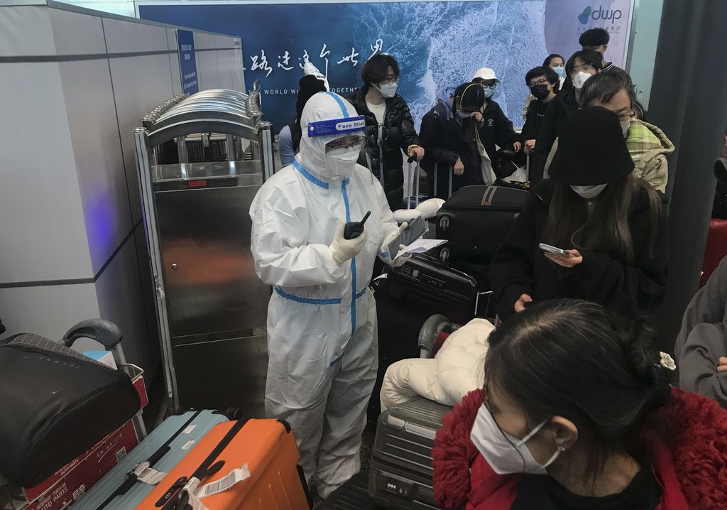Para pelancong tengah menunggu untuk masuk ke bus yang akan membawa mereka dari Bandara Guangzhou Baiyun, Guandong menuju hotel untuk karantina pada Minggu (25/12/2022).