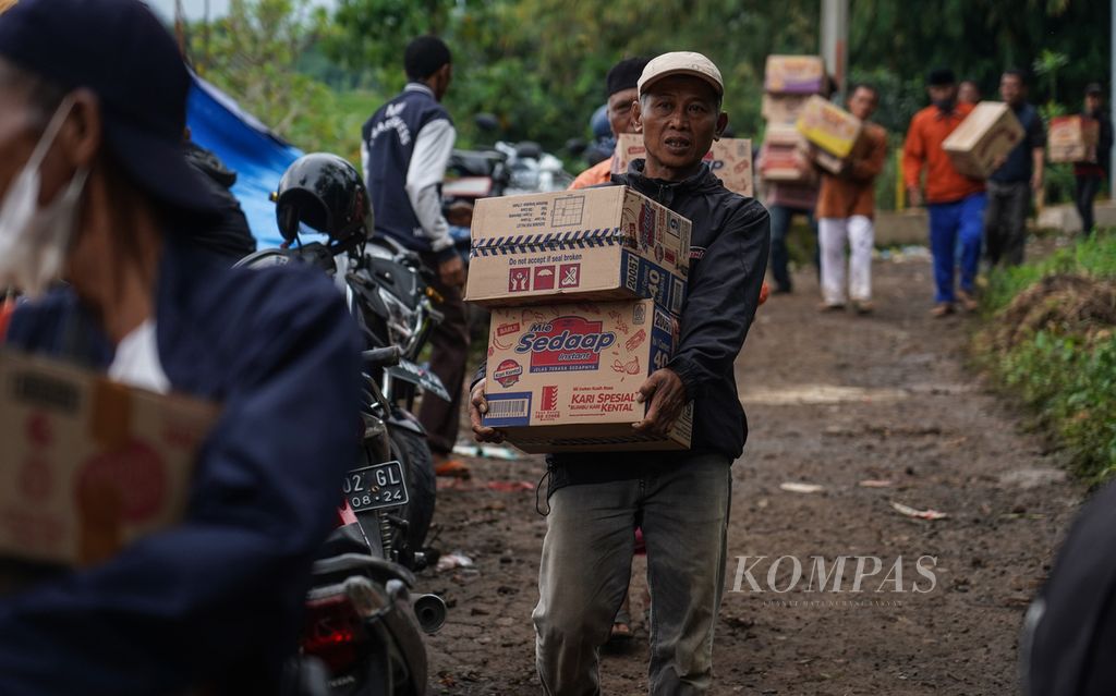 Warga membawa bantuan ke pengungsian di Kampung Rawacina, Nagrak, Kecamatan Cianjur, Kabupaten Cianjur, Jawa Barat, Rabu (23/11/2022). Pascagempa, warga masih memilih mengungsi di ruang terbuka, termasuk pemakaman umum. Di Kampung Rawacina, sembilan warga meninggal akibat gempa.